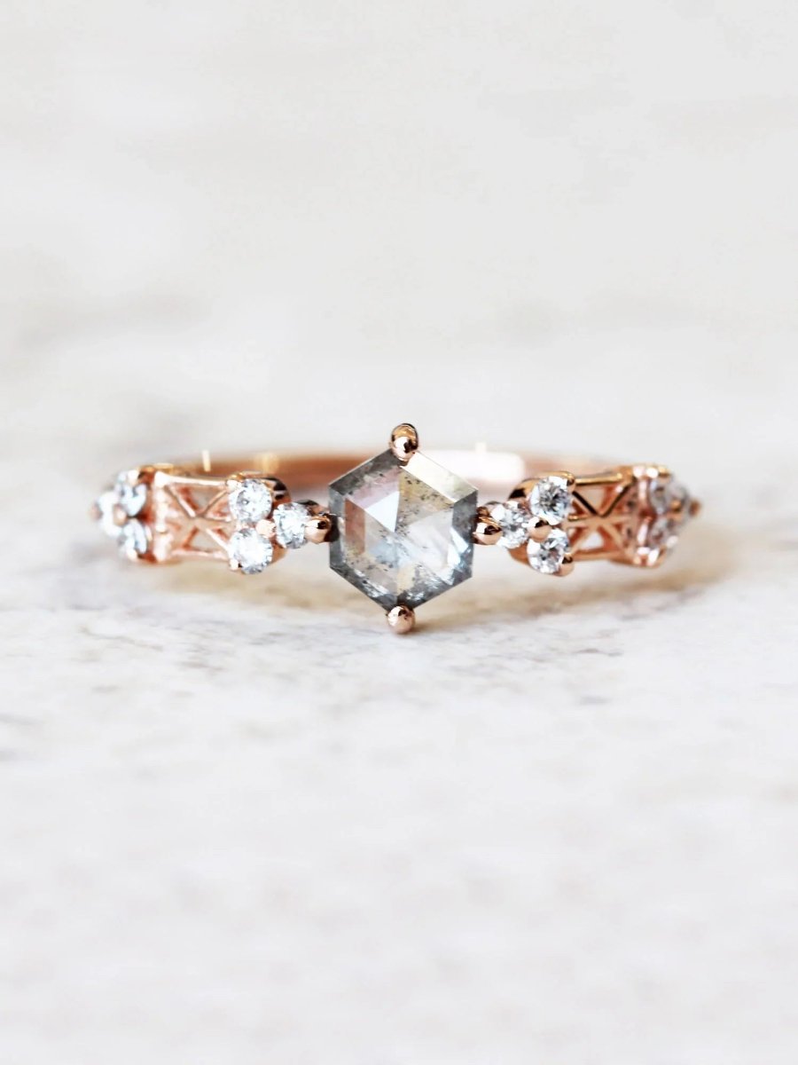 face of Modern Art Deco engagement ring with a salt and pepper hexagon diamond center, round trefoil clusters, architectural latticework on white marble top