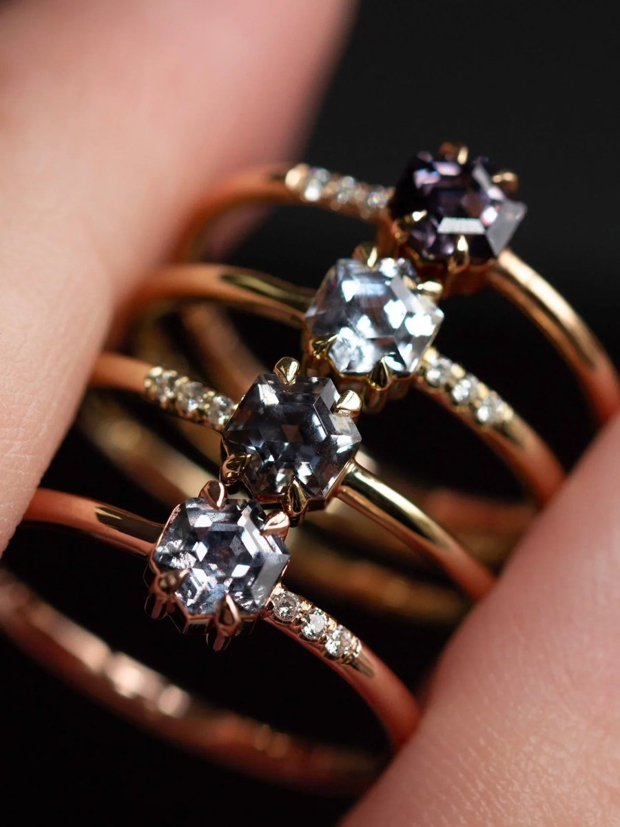 Close-up of a hand wearing two rose gold rings with diamond-like stones.