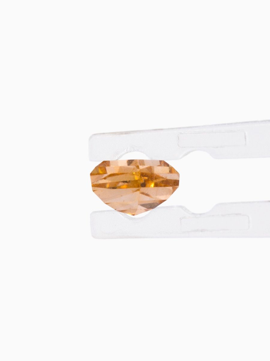 Loose kite-shaped champagne diamond with step cut, side view, held by tweezers