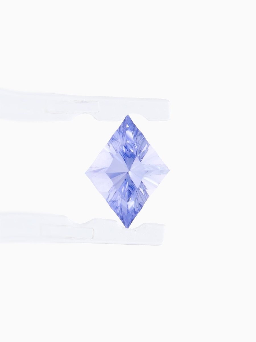 face view of designer cut blue kite sapphire held between tweezers on a white background