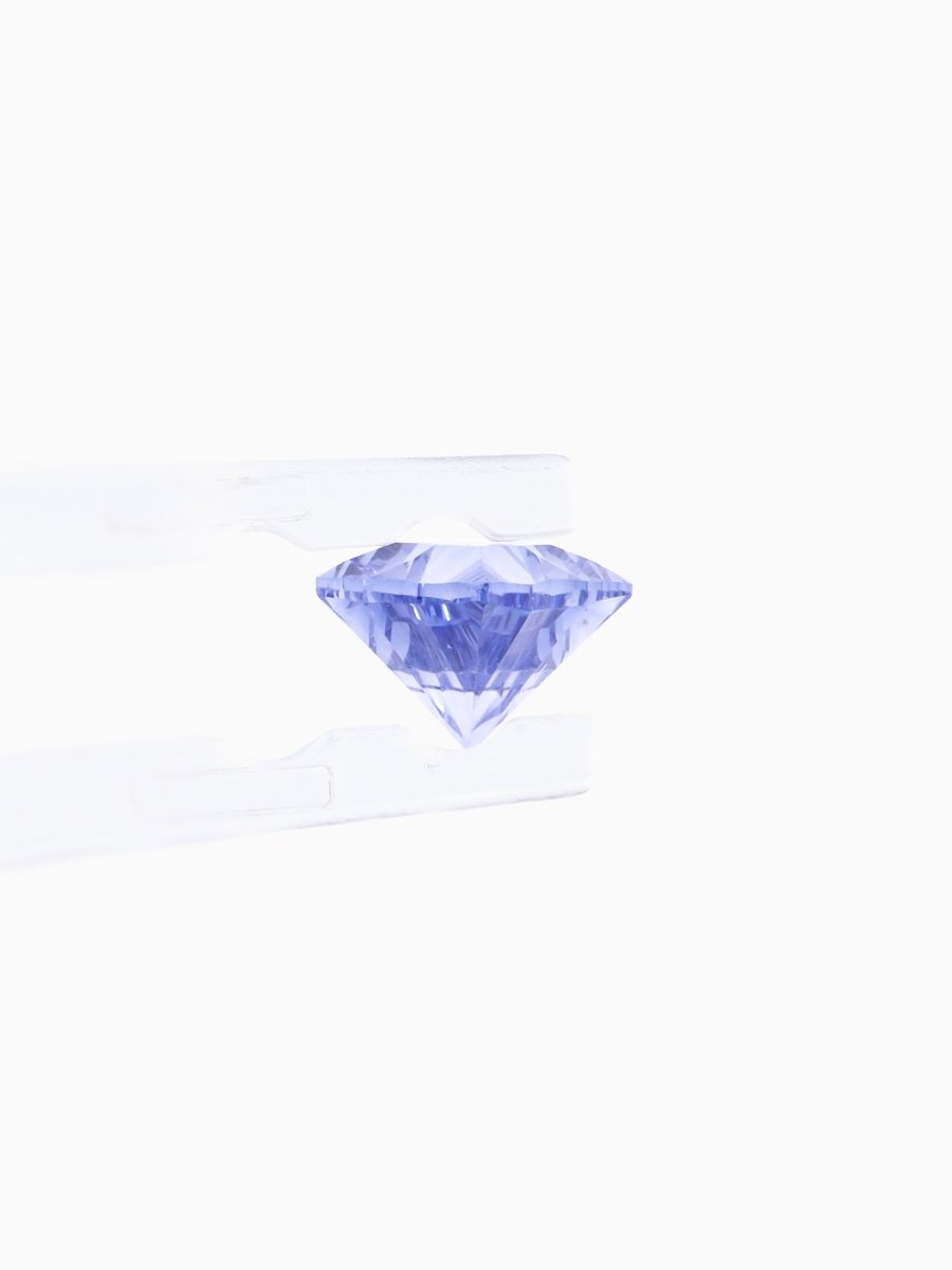 profile of blue sapphire held by tweezers on white background