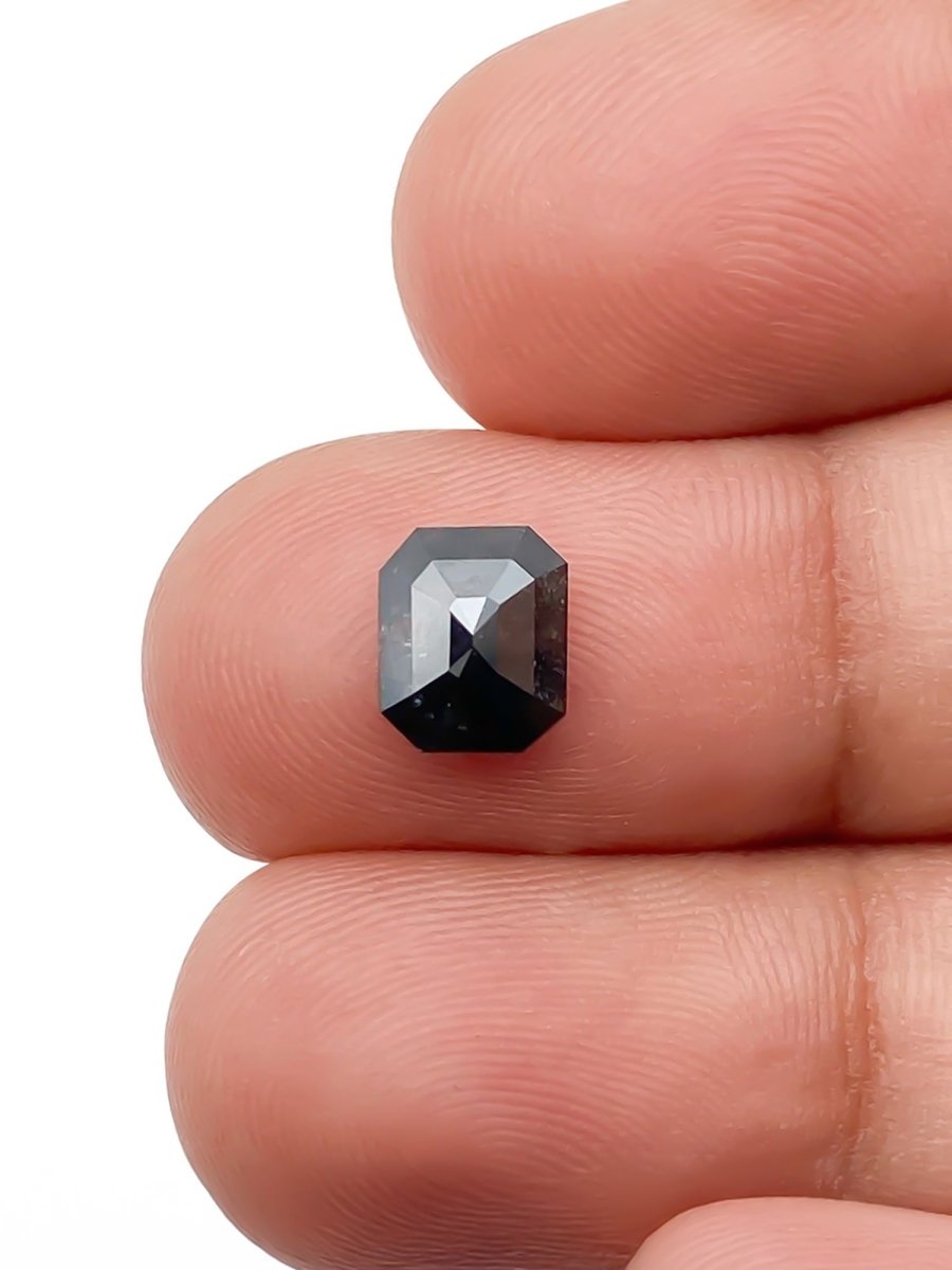 sustainable lab-grown emerald shaped salt pepper diamond between fingers for scale