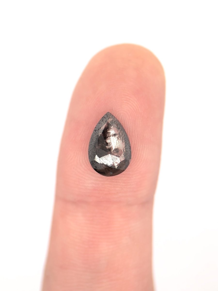 face view of loose lab-grown hexagon salt pepper diamond gemstone on finger for scale