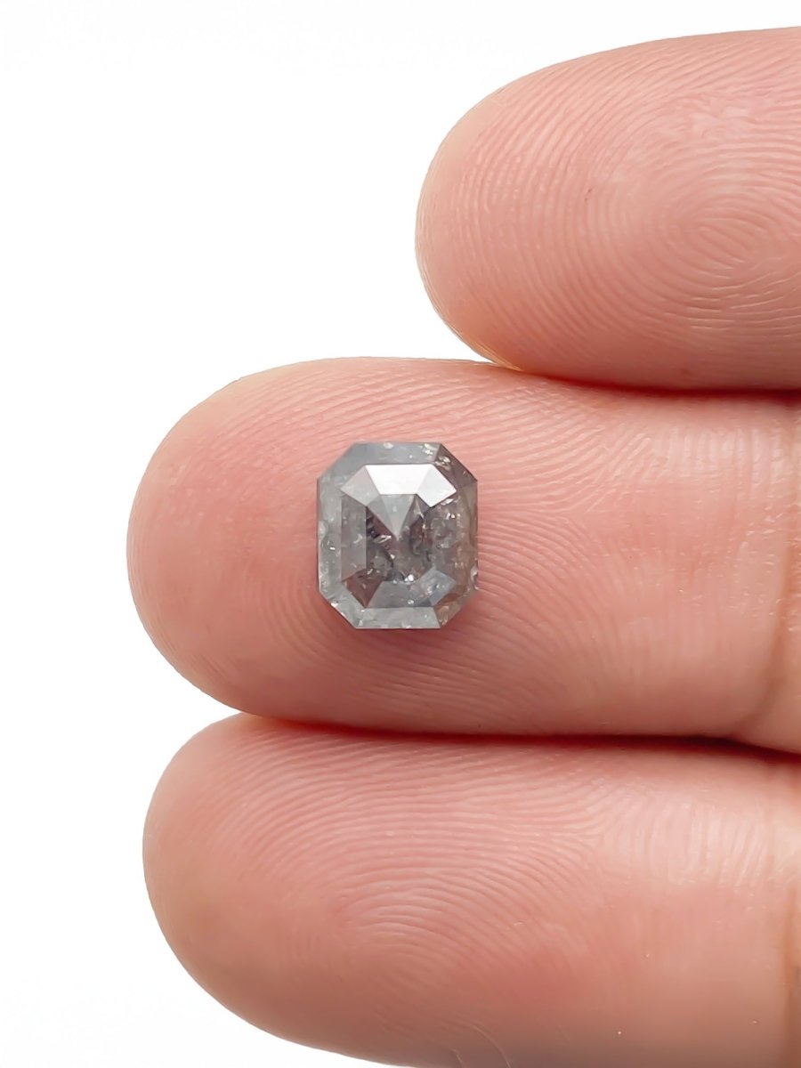 sustainable lab-grown emerald shaped salt pepper diamond between fingers for scale