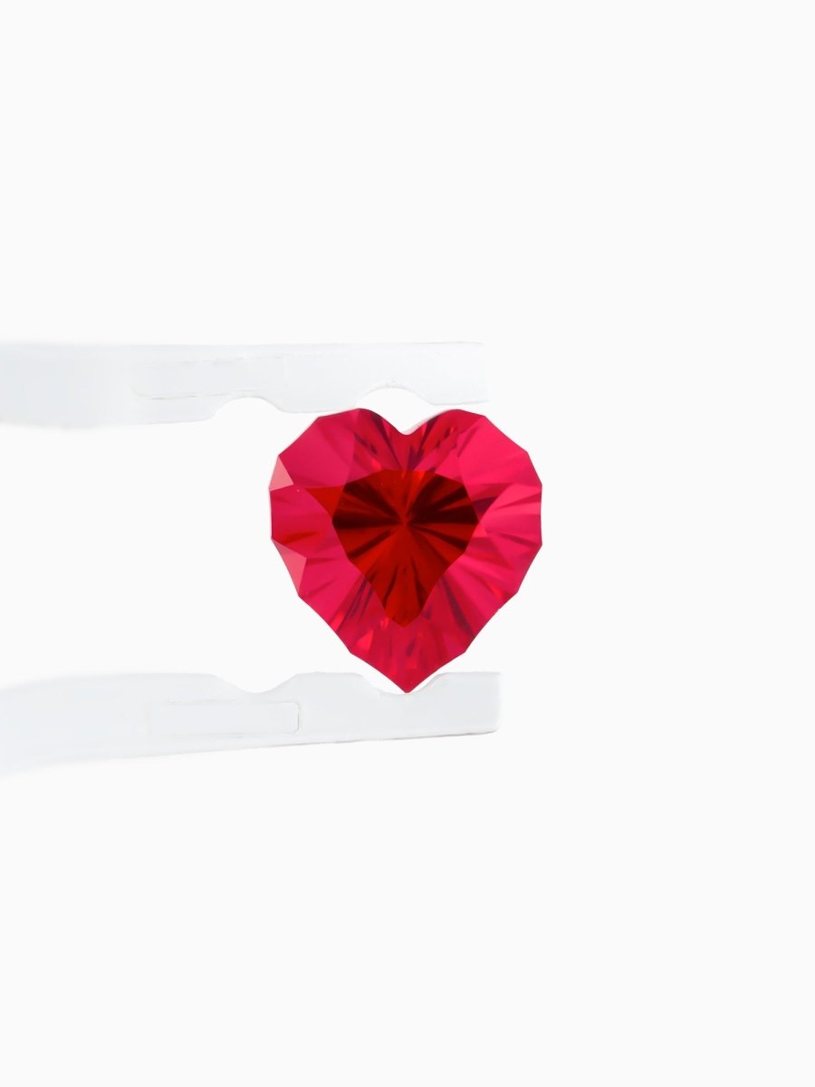 face view of designer cut red heart sapphire held between tweezers on a white background