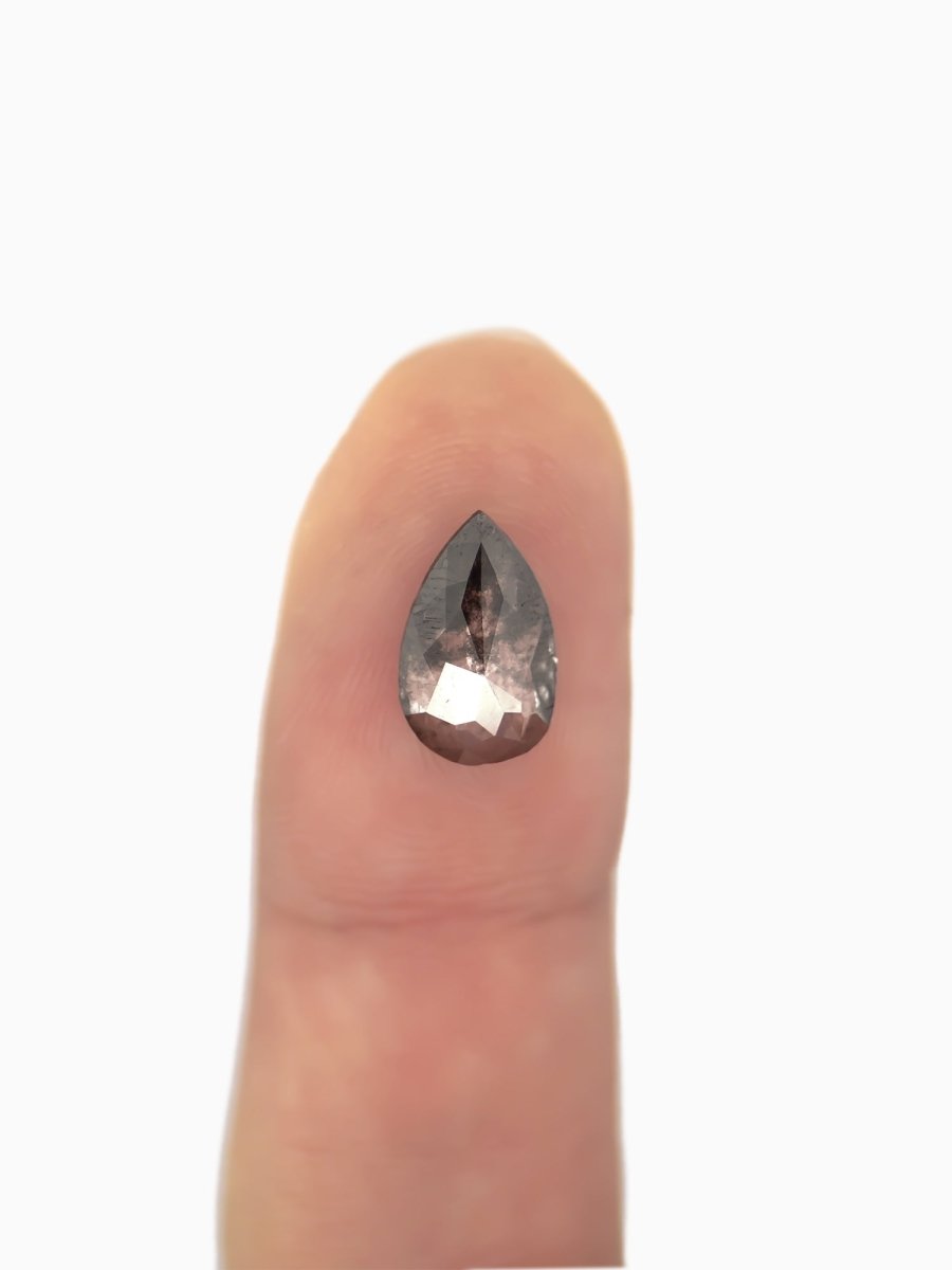 face view of loose lab-grown pear salt pepper diamond gemstone on fingertip for scale