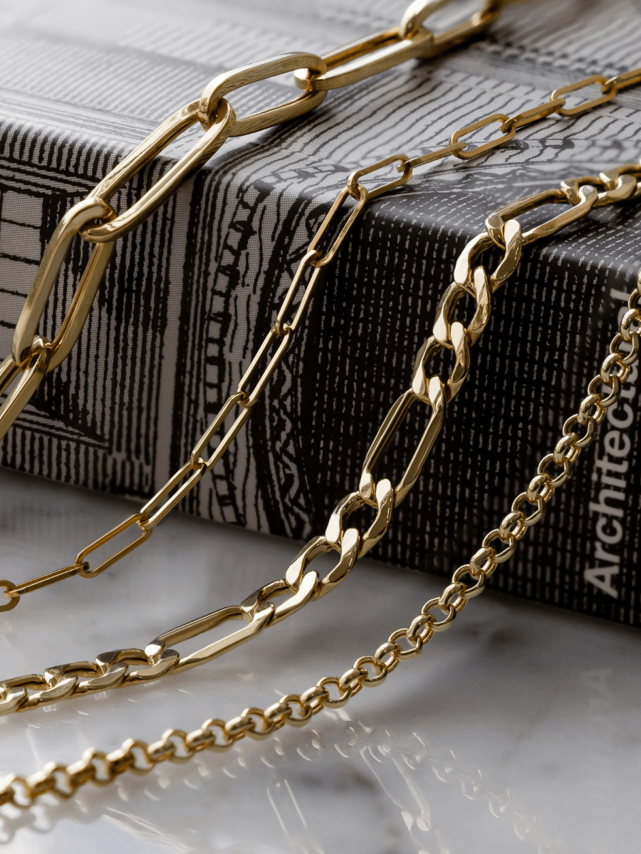 variety of gold chains laid across black and white book binding