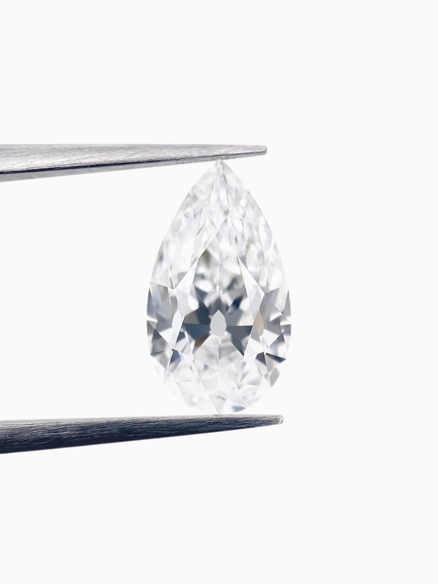 Pear-shaped diamond held between tweezers on a white background