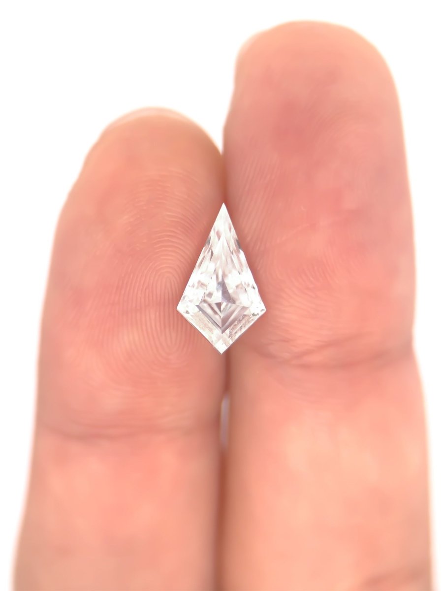 Top view of loose lab-grown kite shaped moissanite gemstone on finger, showing scale, sustainable and conflict-free