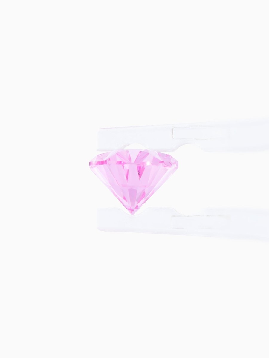 profile of pink sapphire held by tweezers on white background
