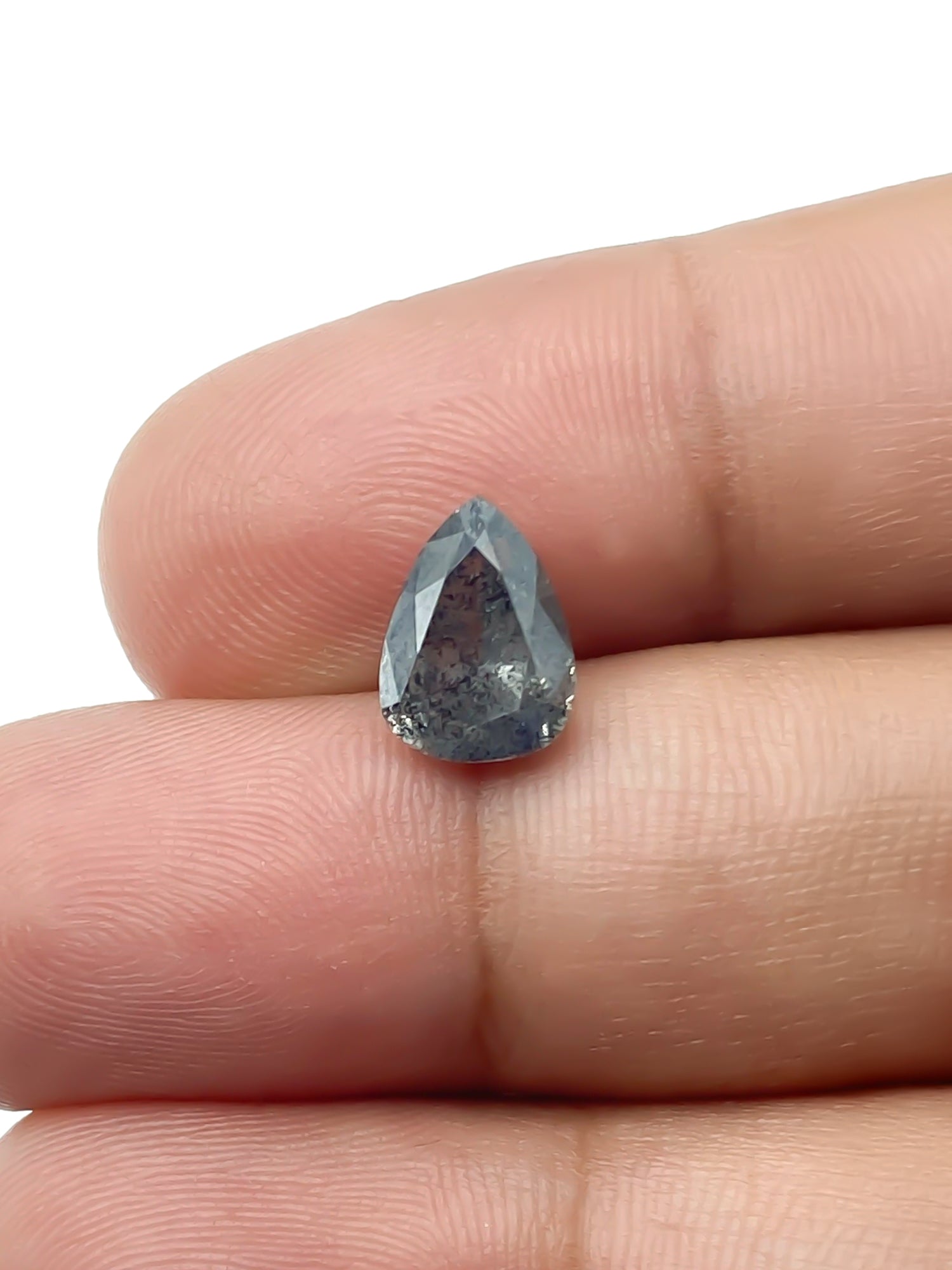 sustainable lab-grown pear shaped salt pepper diamond between fingers for scale