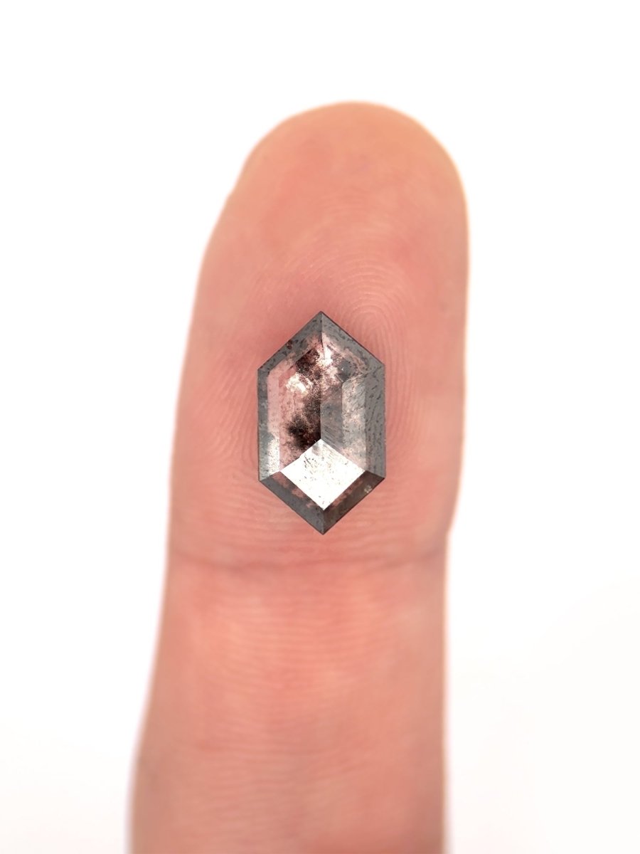 face view of loose lab-grown hexagon salt pepper diamond gemstone on finger for scale