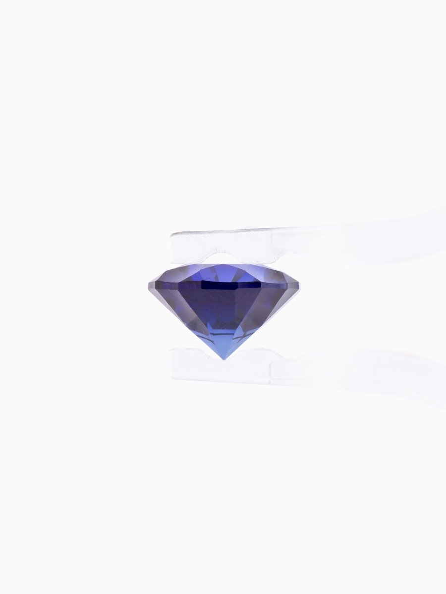 profile of blue sapphire held by tweezers on white background