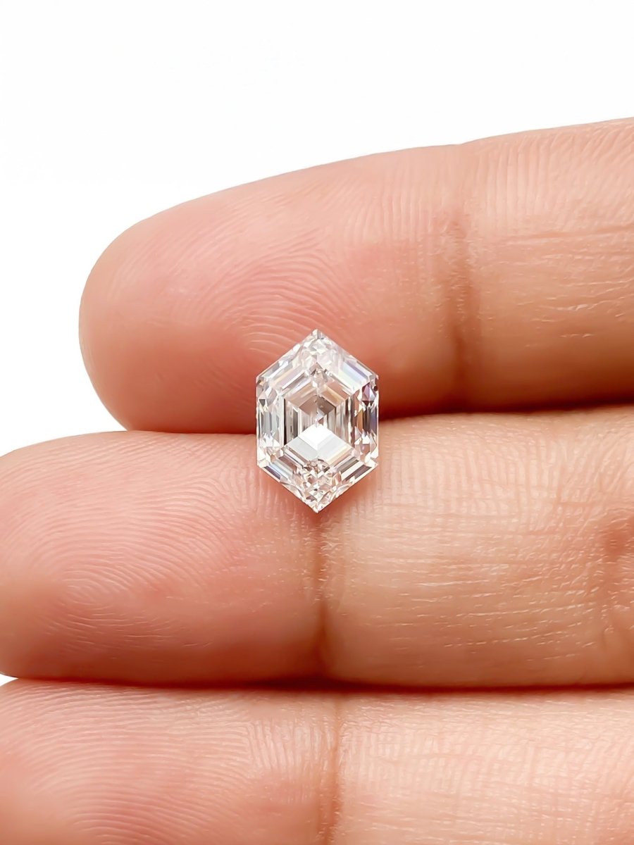 lab grown sustainable hexagon white diamond on white background between fingers for scale