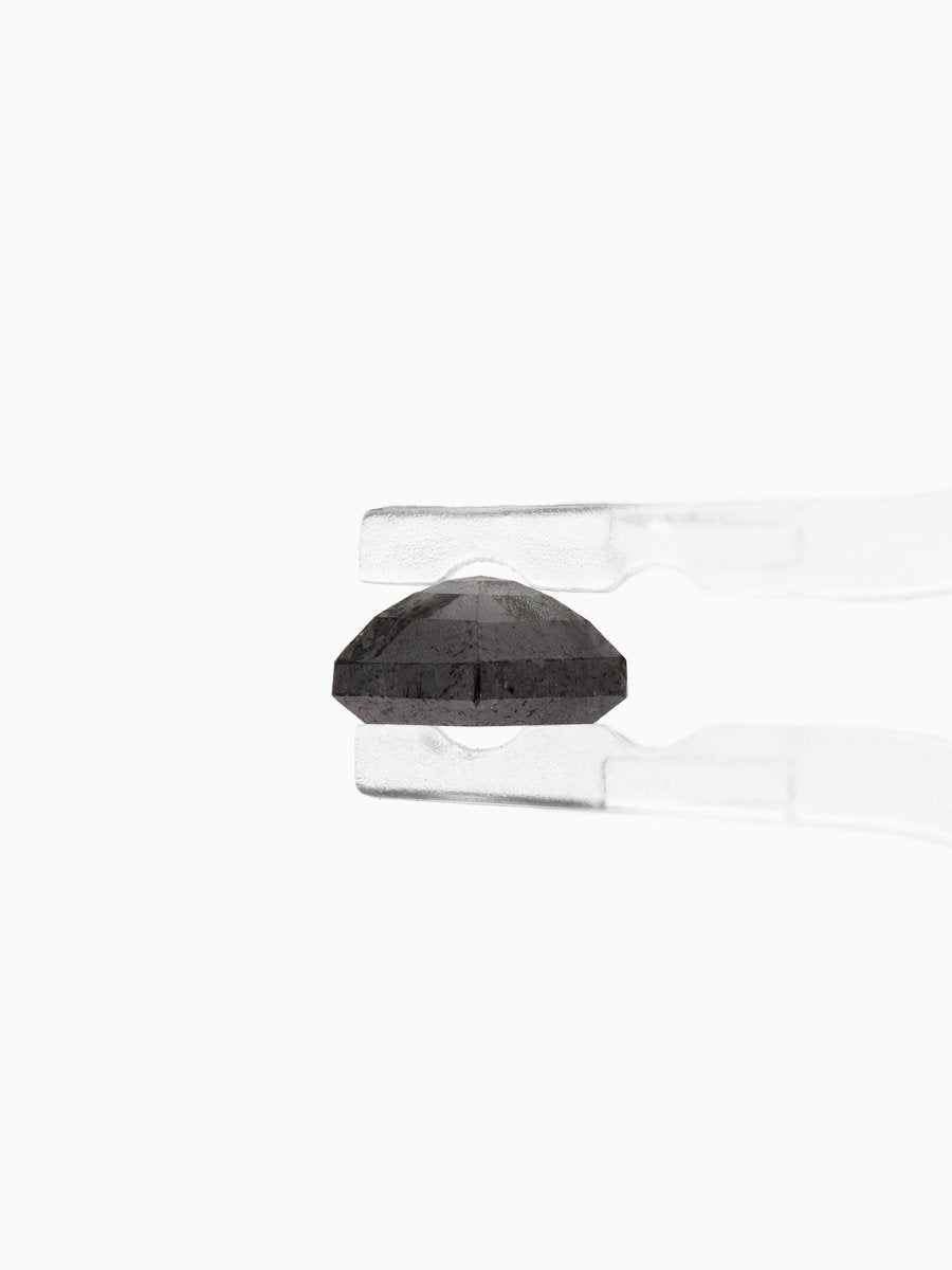 profile view of loose lab-grown hexagon salt pepper diamond gemstone held by tweezers
