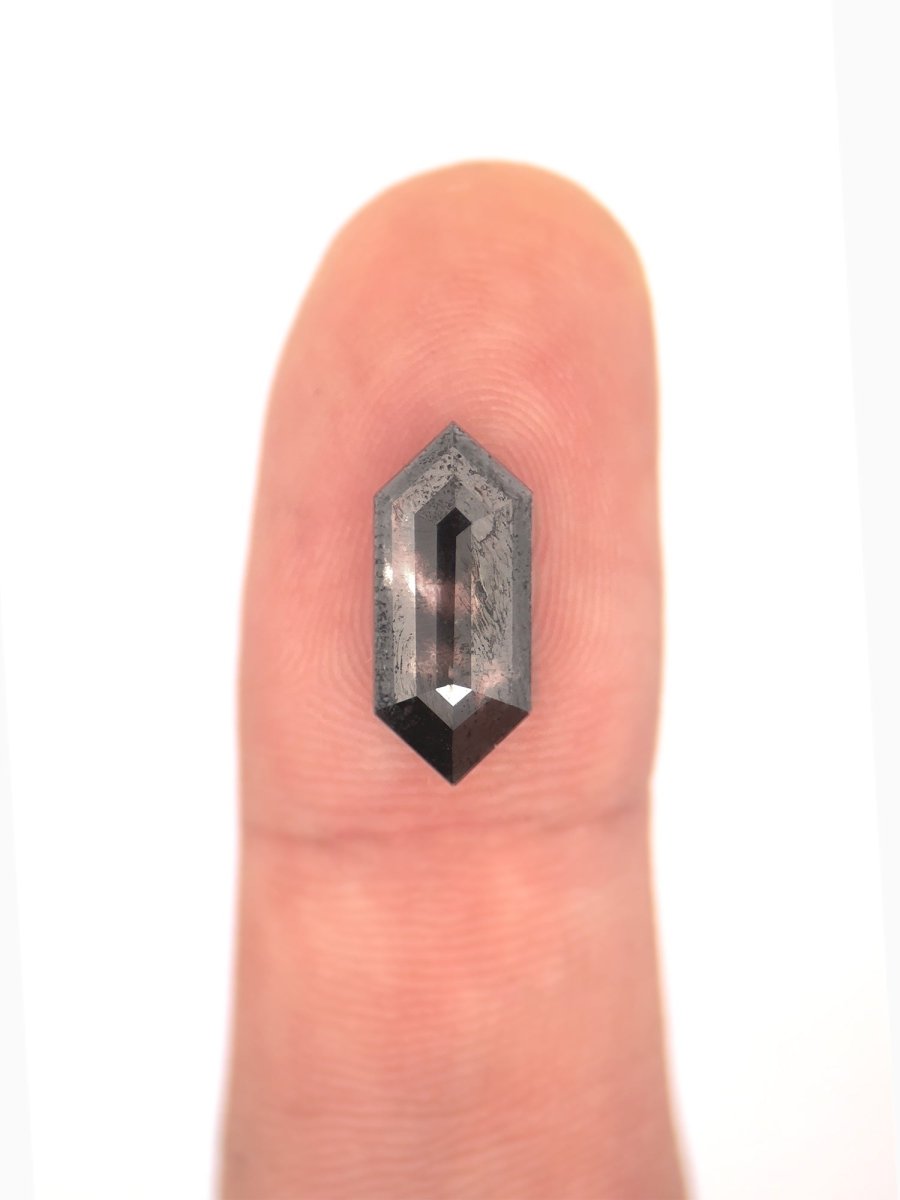 face view of loose lab-grown hexagon salt pepper diamond gemstone on finger for scale