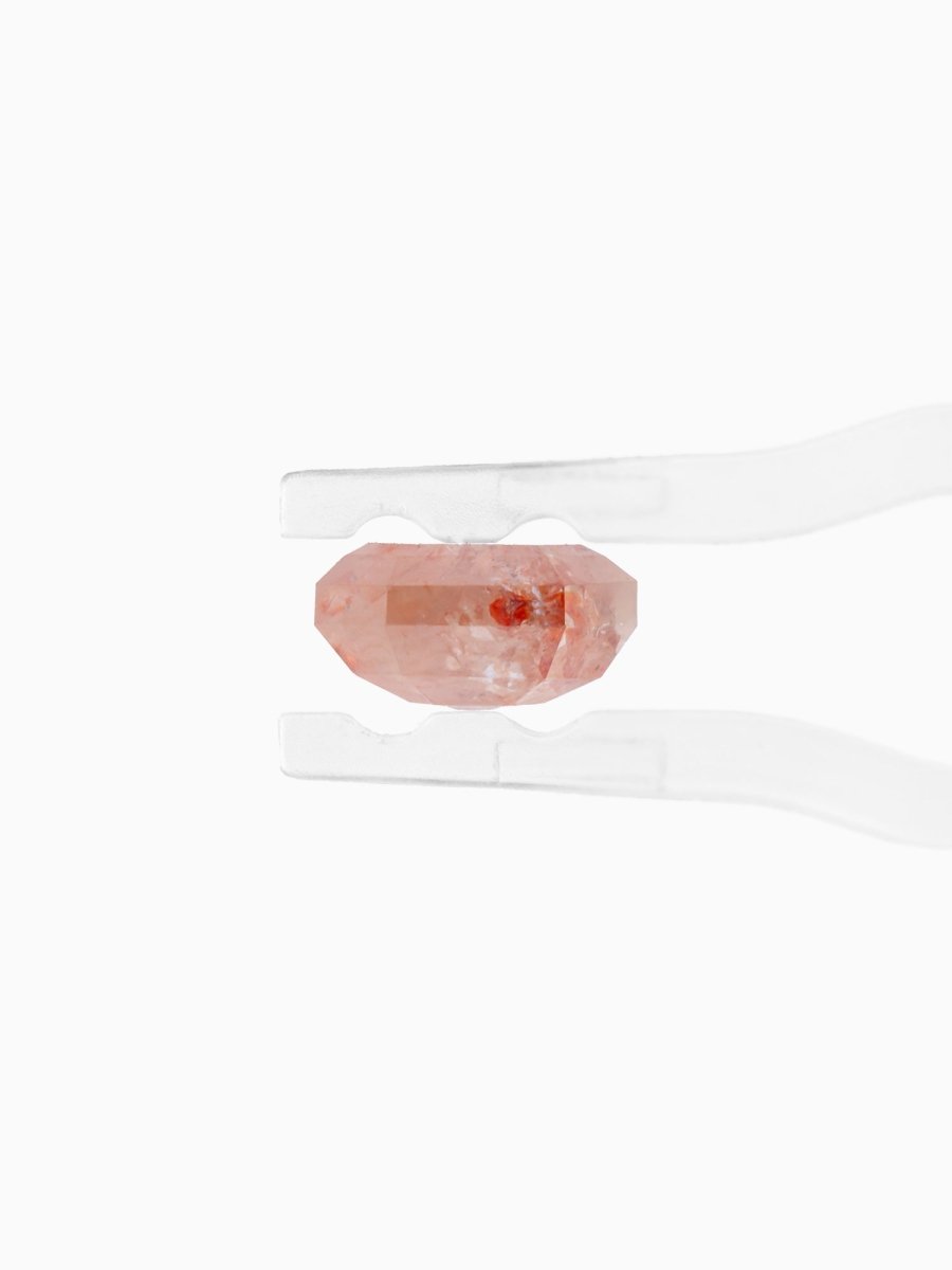 side view of loose lab-grown emerald-cut rose salt pepper diamond gemstone between tweezers