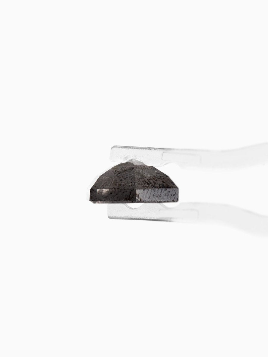 profile view of loose lab-grown hexagon salt pepper diamond gemstone held by tweezers
