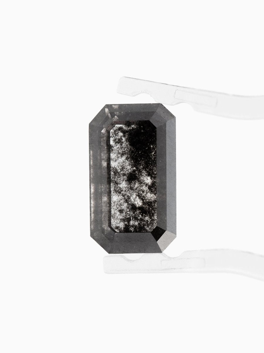 face view of loose lab-grown emerald-cut salt pepper diamond gemstone held by tweezers