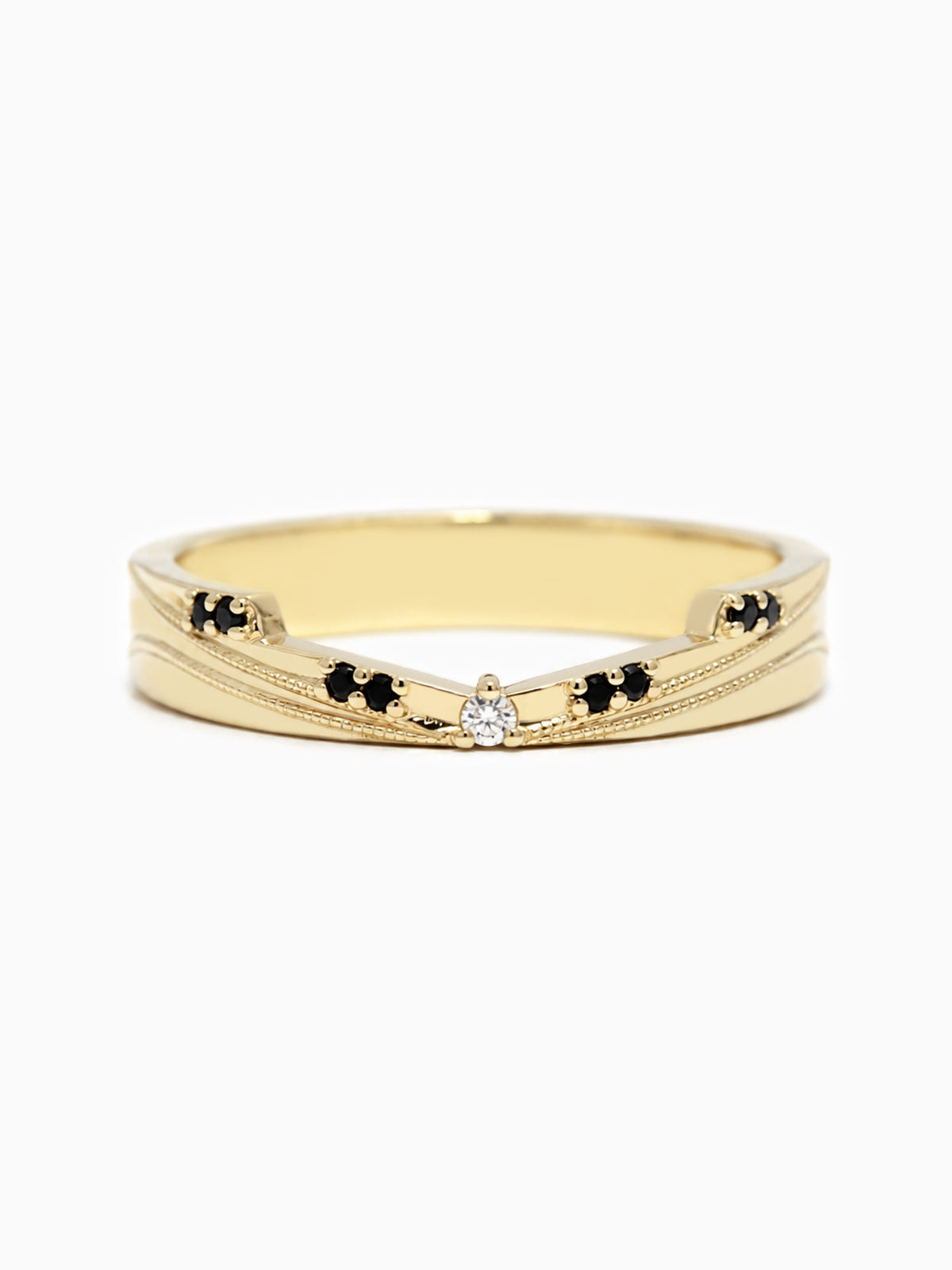 A gold band ring featuring a textured chevron design with small black diamond accents on either side of a central clear round-cut gemstone, shown on a plain white background.