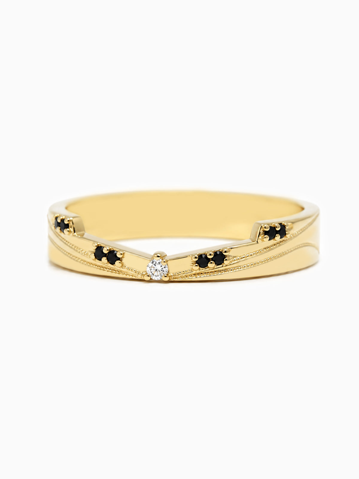 A gold band ring featuring a central clear round-cut gemstone flanked by small clusters of black stones, set against a plain white background.