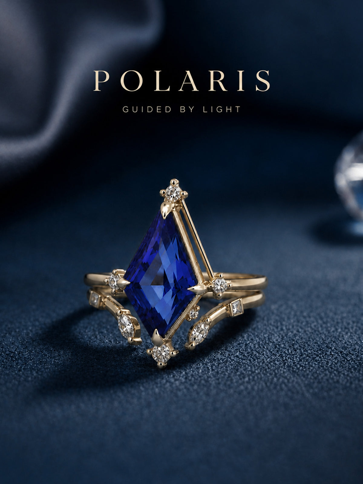 A gold ring featuring a large, faceted blue gemstone in a geometric setting, accented with small clear stones, displayed on a dark navy textured surface with the brand name 'POLARIS' at the top.