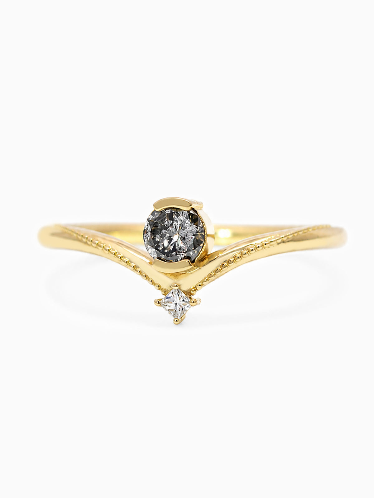 A yellow gold ring featuring a round black diamond center stone and a smaller clear diamond accent below, set against a plain white background.