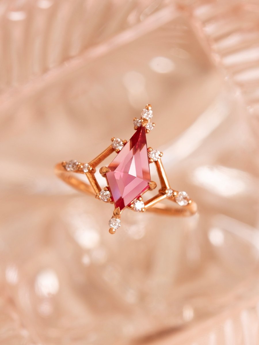Rose gold ring with a pink gemstone on a soft pink background