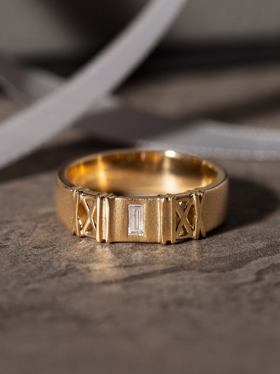 Sandblasted gold band with a diamond on a textured surface