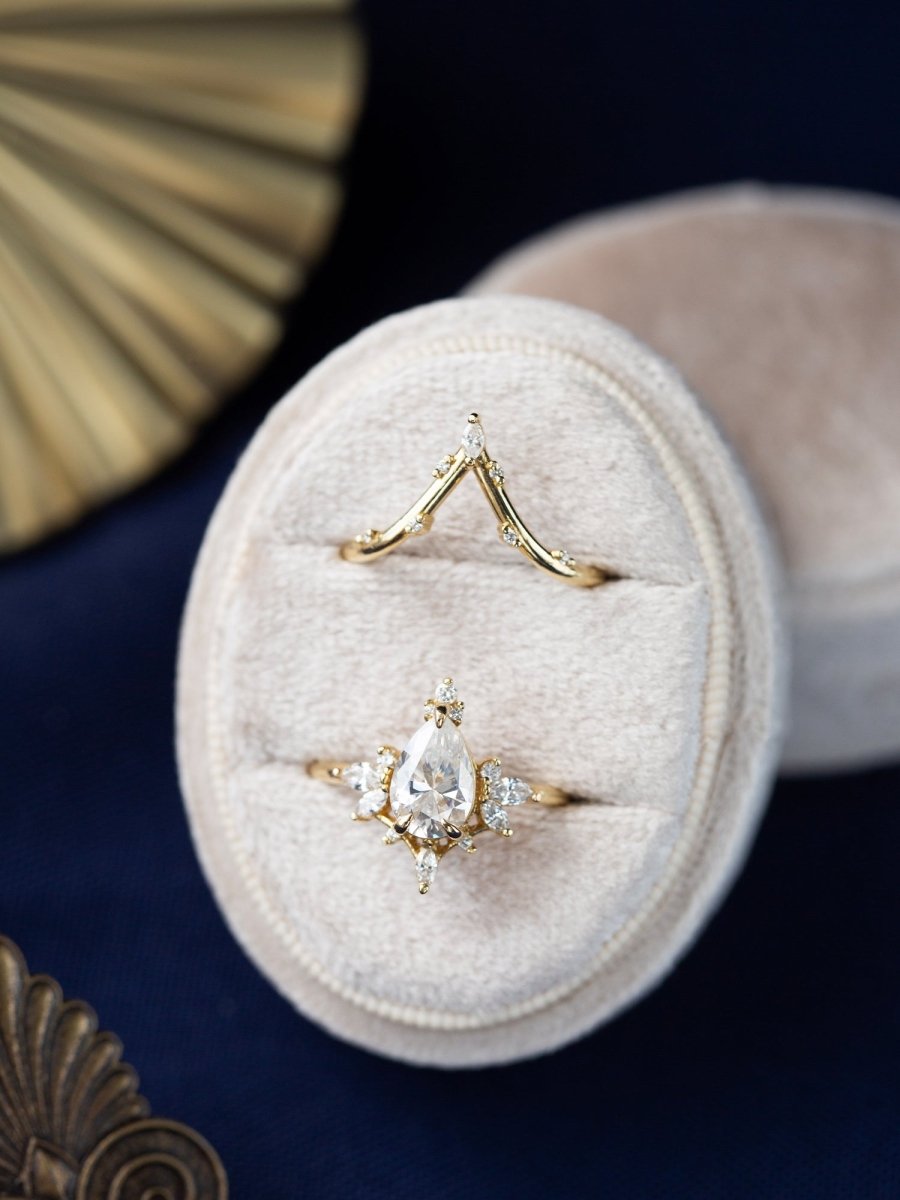 Vintage-modern Art Deco ring with matching band in white box, surrounded by bronze ornaments for a luxe display