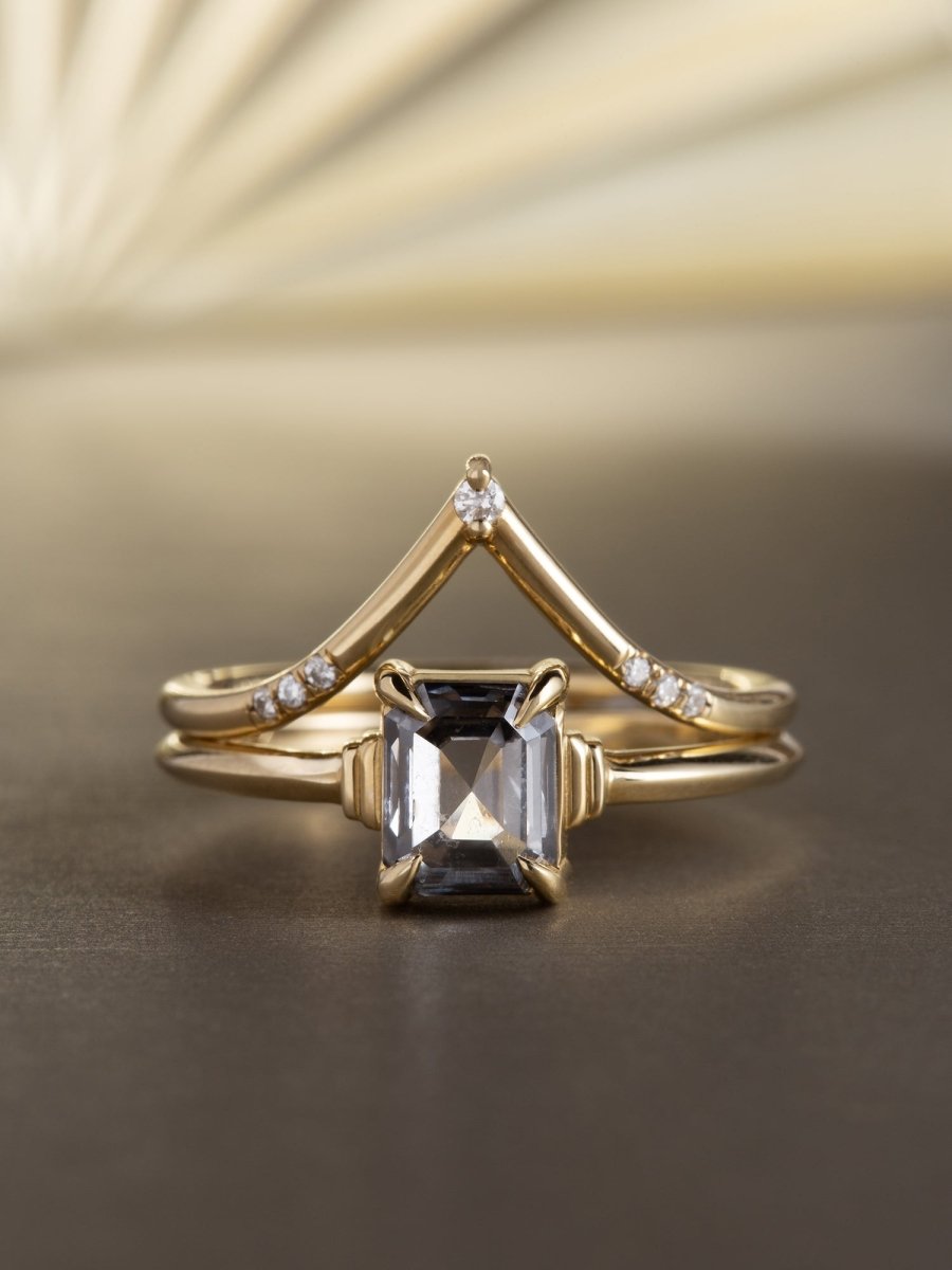 Gold ring with a central gemstone and smaller diamonds on a gradient background