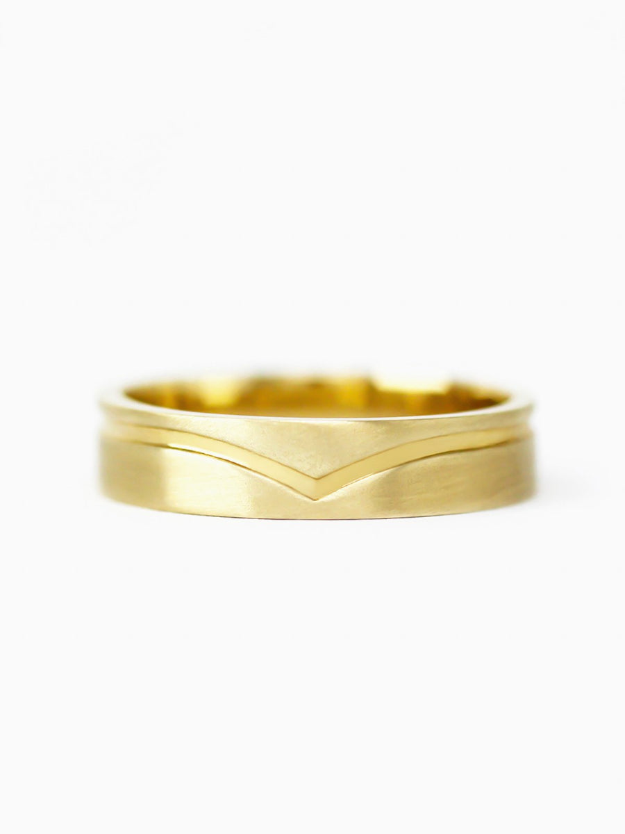 Gold ring with wavy design on a white background