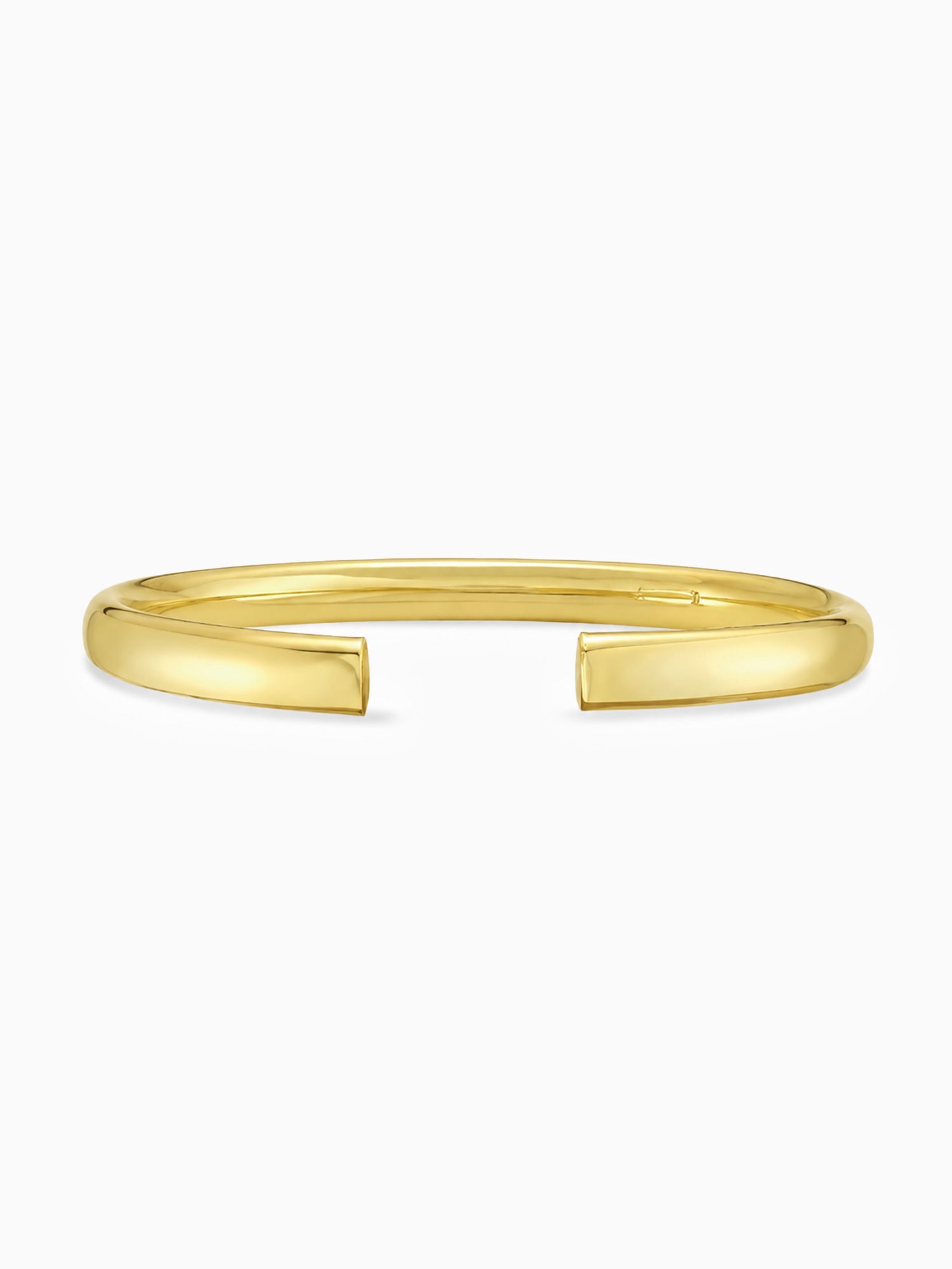 A polished yellow gold open cuff bangle bracelet, photographed horizontally against a clean, light off-white background.