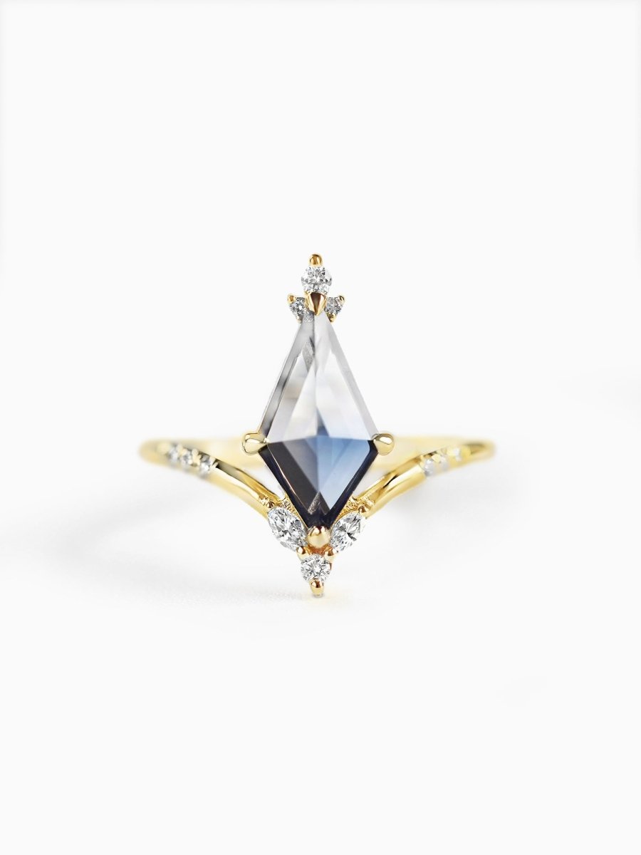 A gold-colored ring with a kite-shaped sapphire centerpiece and smaller diamond accents around it.