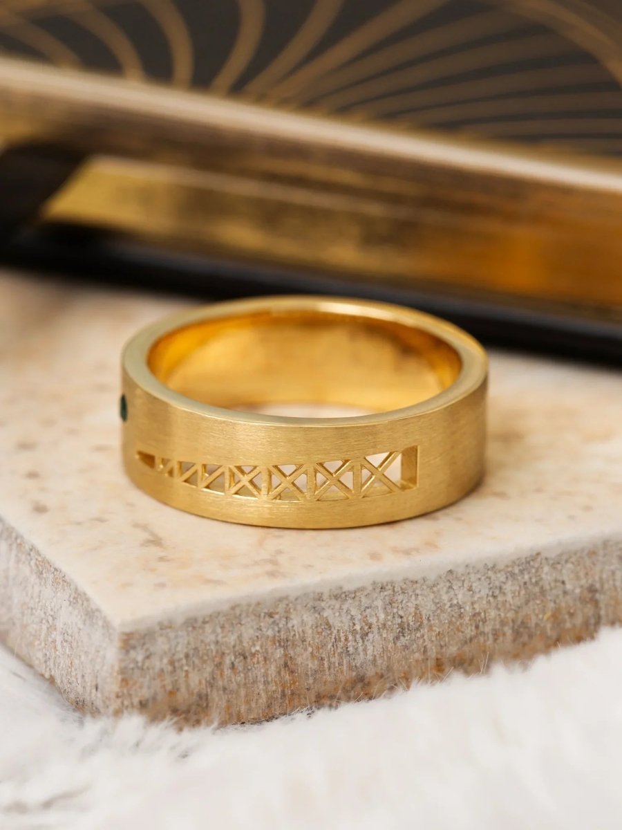 Gold ring with intricate design on a textured surface