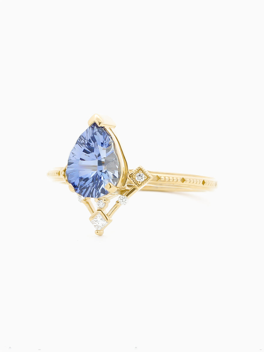 Art Deco–inspired ring with designer-cut blue pear and radiating detail on white background, 3/4 View to show milgrain details