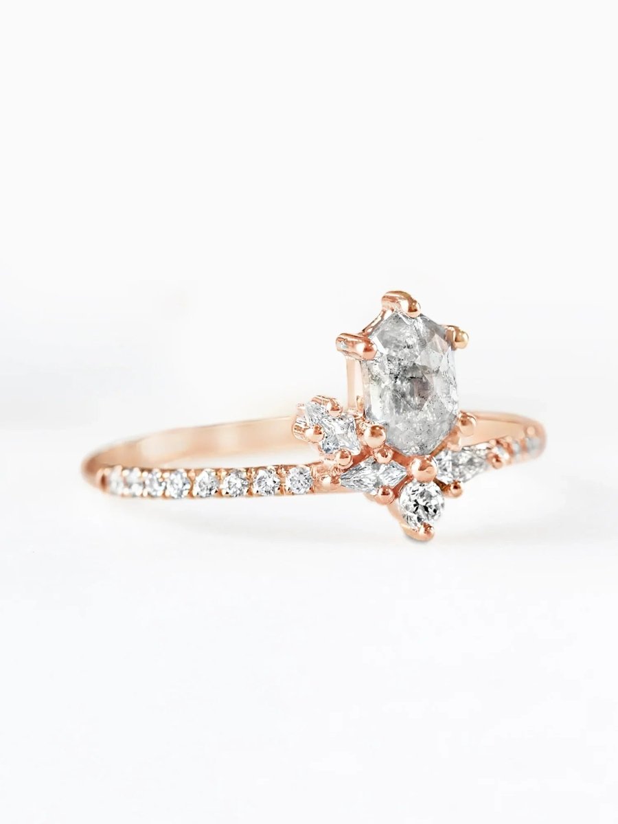 Rose gold ring with a central diamond and smaller diamonds on a white background