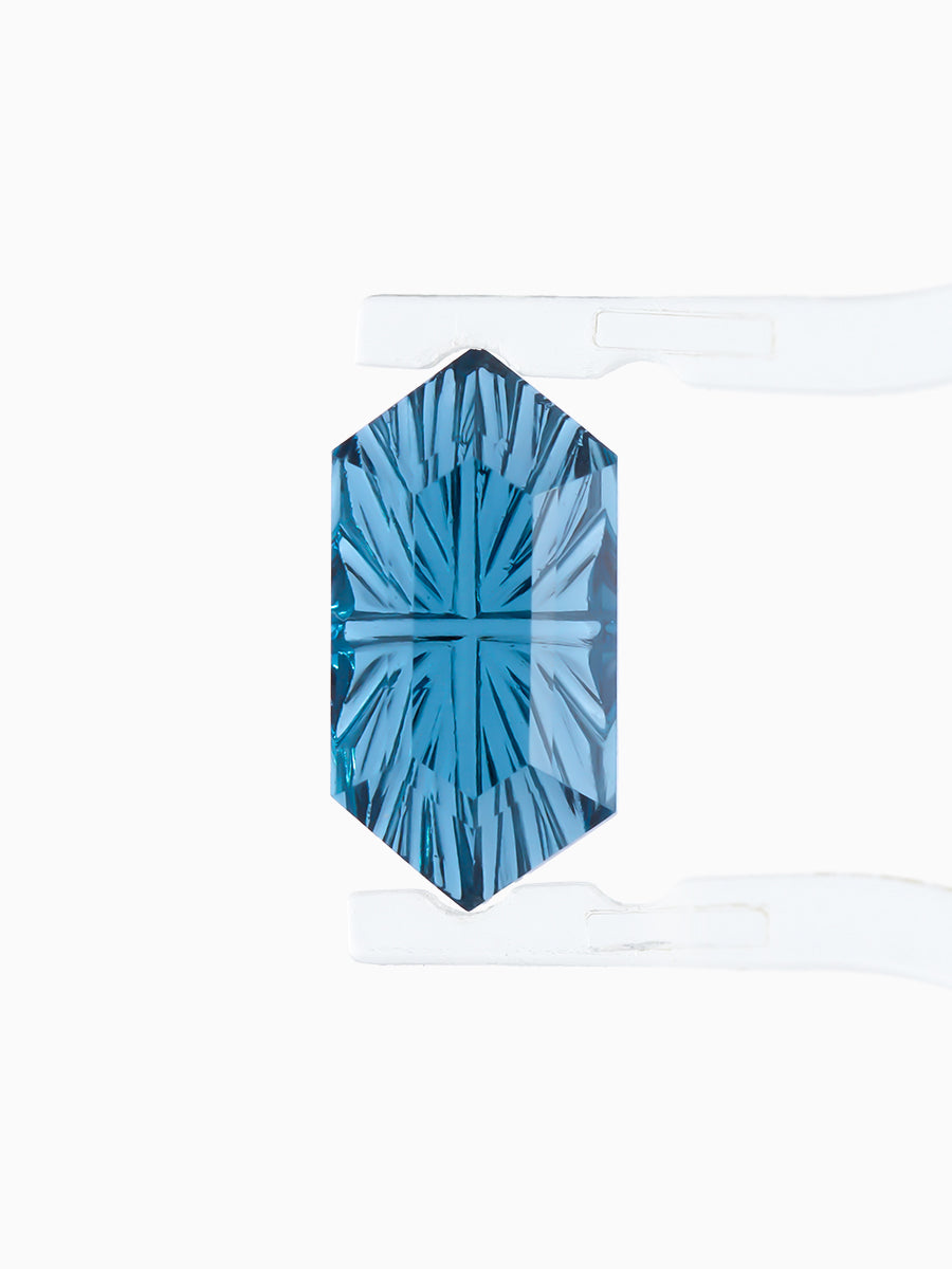 lab grown fantasy cut deep blue topaz hexagon held by tweezers, focusing on radiating faceted pavilion