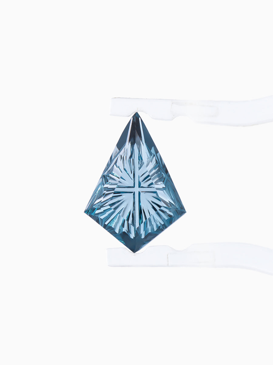 lab grown fantasy cut deep blue topaz kite held by tweezers, focusing on radiating faceted pavilion