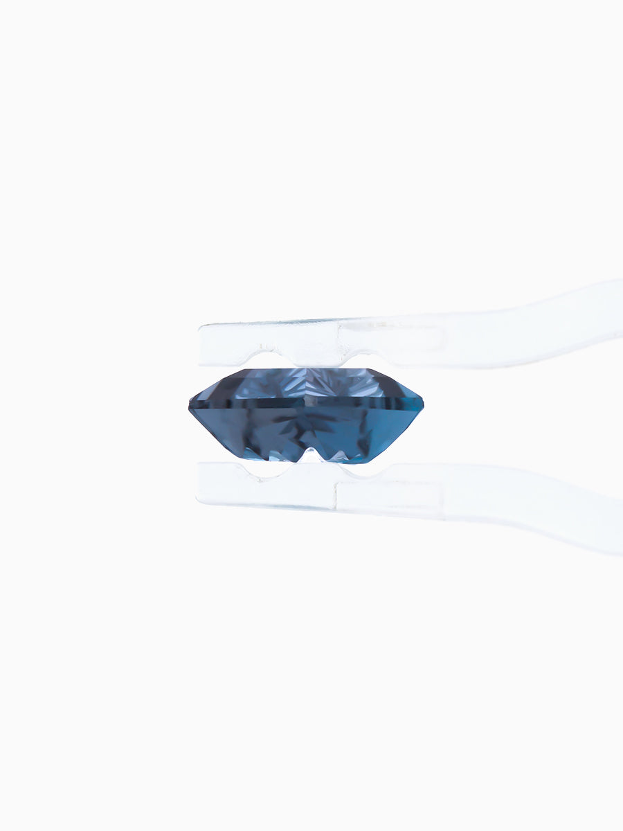 lab grown fantasy cut deep blue topaz kite held by tweezers, profile view