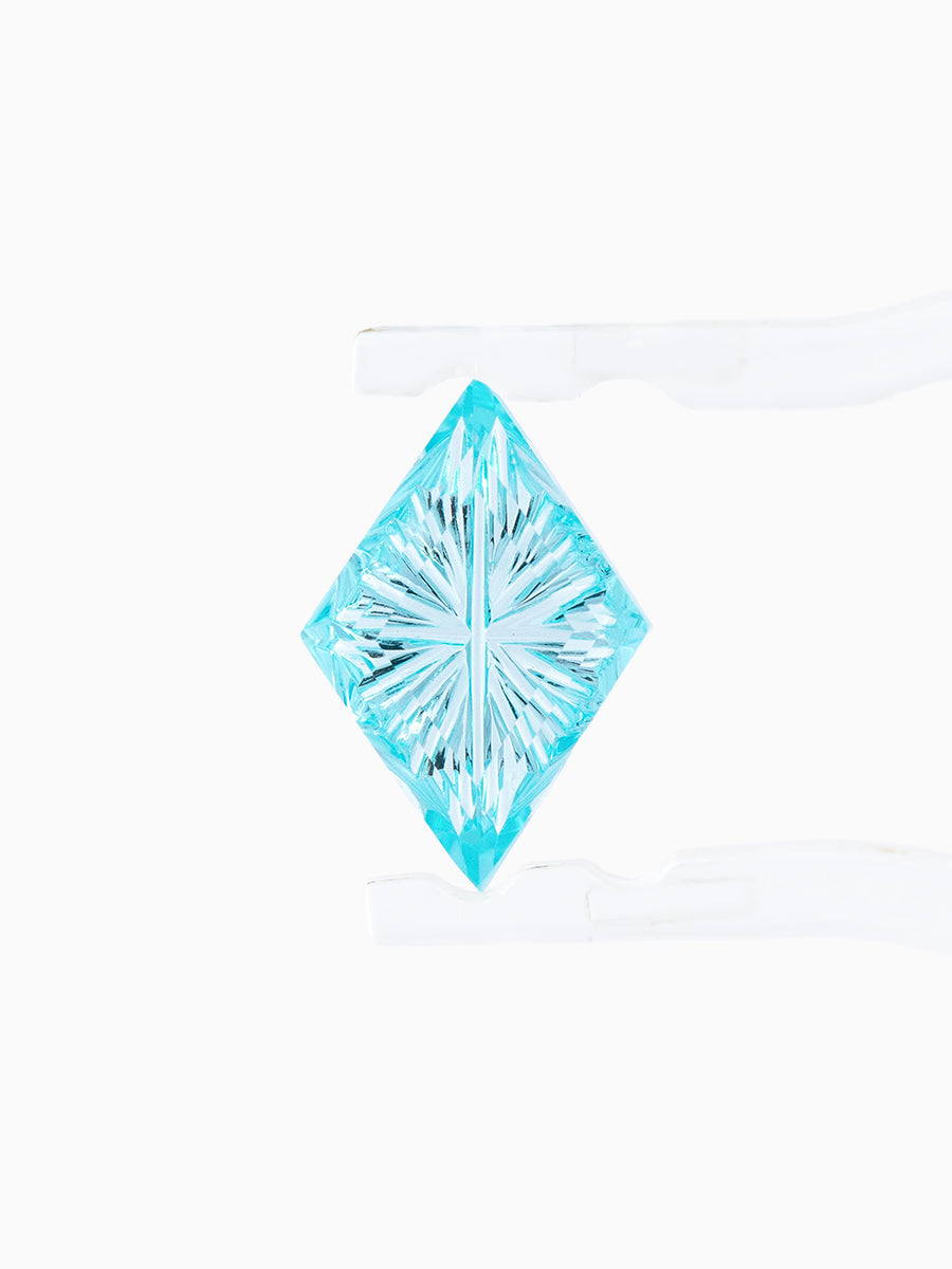 lab grown fantasy cut teal sapphire kite held by tweezers, focusing on radiating faceted pavilion