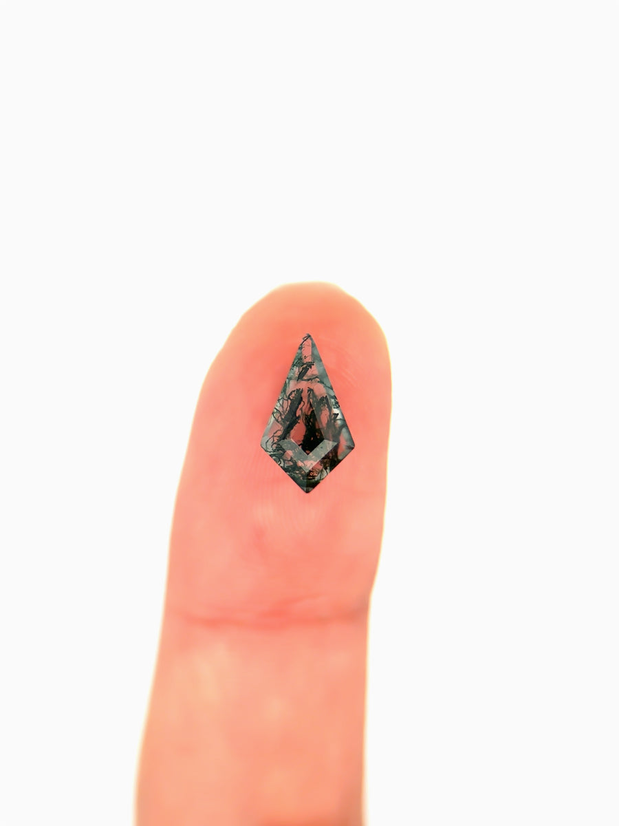 Kite-shaped loose moss agate gemstone with dendritic green inclusions  on finger for scale