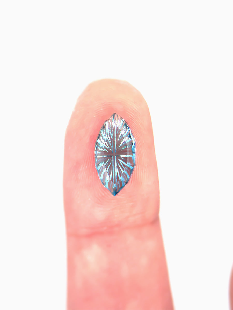 sky blue marquise garnet  with sunbursts cut into its pavilion placed on fingers for scale