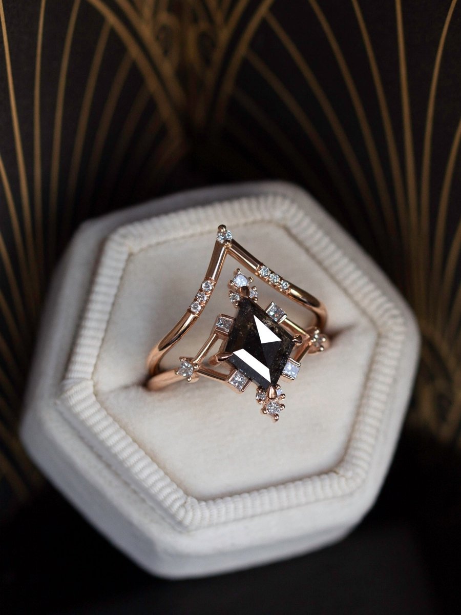 Rose gold ring with a black gemstone in a hexagonal white box against a dark background