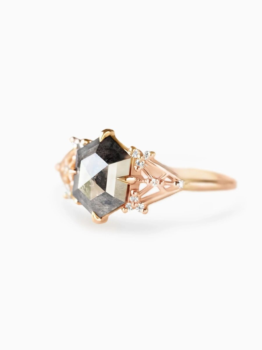 Rose gold ring with a large diamond and smaller stones on a white background
