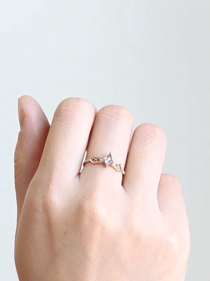 GIF of hand wearing sparkling petite modern geometric Art Deco salt & pepper kite engagement ring on middle finger as fingers uncurl