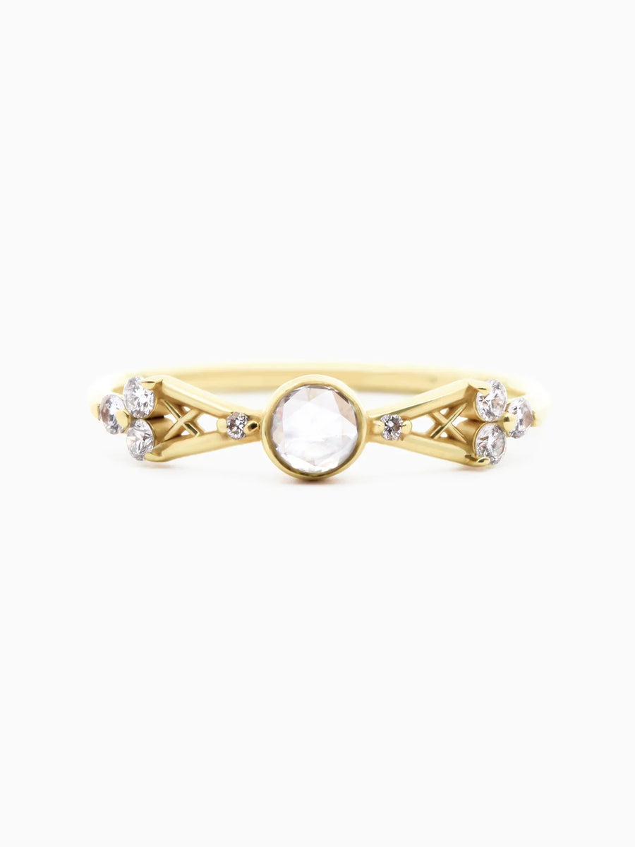 Face view of petite contemporary Art Deco yellow gold ring with open-back bezel-set round diamond, tapered lattice shank, and trefoil clusters