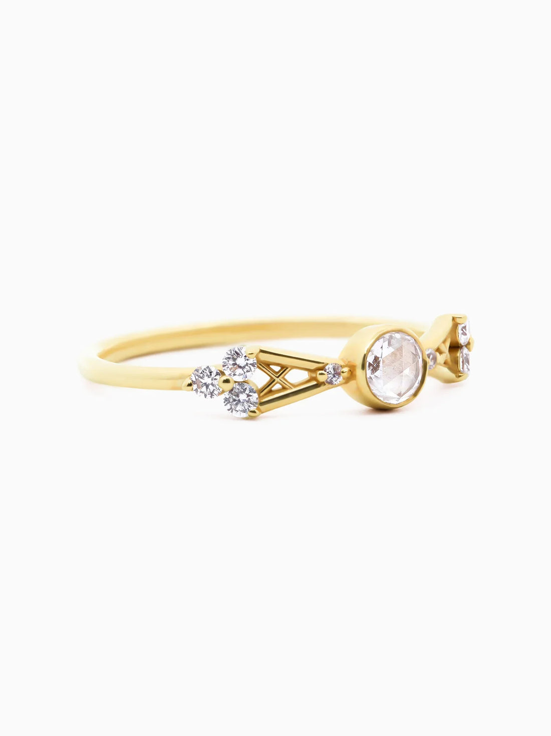 3/4 view of petite contemporary Art Deco yellow gold ring with open-back bezel-set round diamond, tapered lattice shank, and trefoil clusters