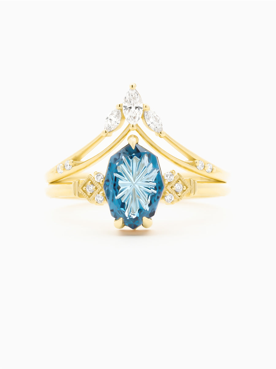 Gold ring with a blue gemstone and diamond accents on a white background