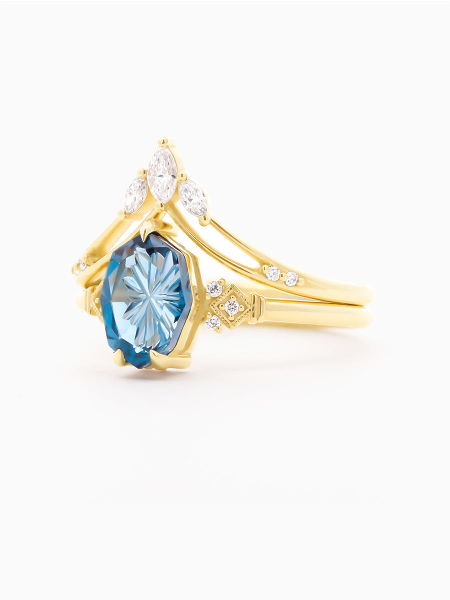 Gold ring with a blue gemstone and smaller diamonds on a white background